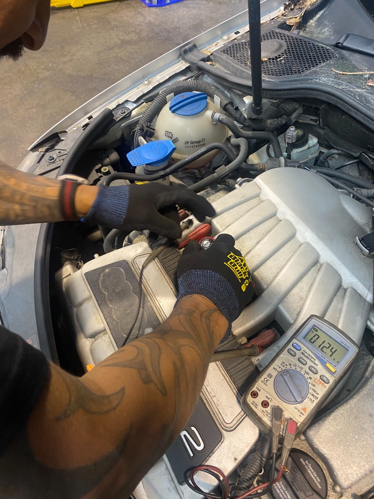 Technician using a multimeter to diagnose an Audi engine