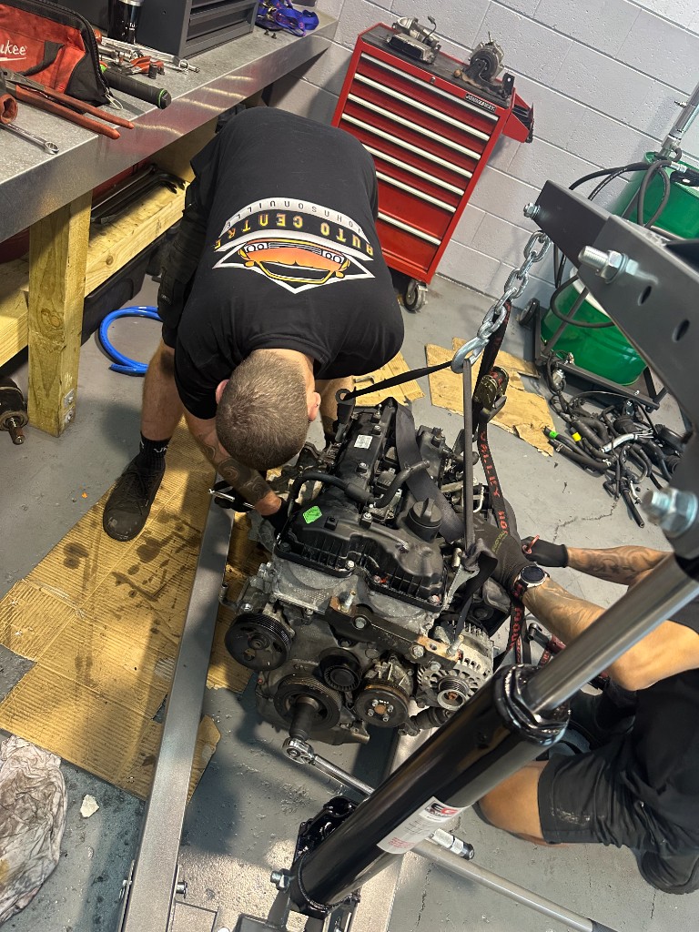 Mechanics using an engine hoist in the Auto Centre Johnsonville workshop