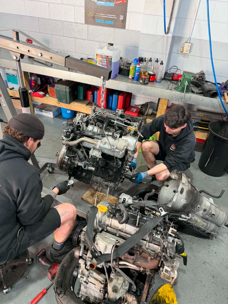 Two technicians working on an engine rebuild in the workshop